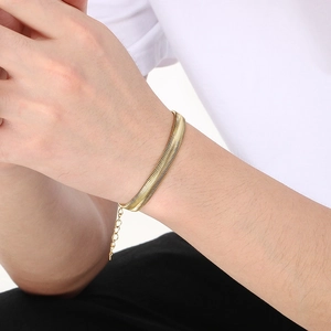 Close-up of a gold flat snake chain bracelet worn on a wrist with adjustable extender