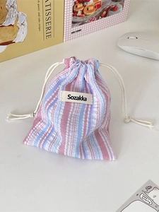 Pink and blue striped drawstring storage pouch with natural texture on a desk