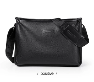 Close-up of black pebble leather shoulder bag with wide strap and embossed brand logo