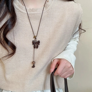 Détail du pendentif nœud léopard et perle en bois sur long collier en cuir marron