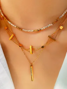 Detail of layered gold necklaces with geometric cubes and micro-pave rhinestone tube pendant