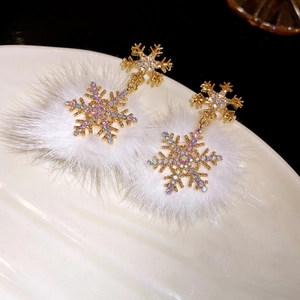 Detail of snowflake earrings with gold finish, sparkling rhinestones and white fur balls