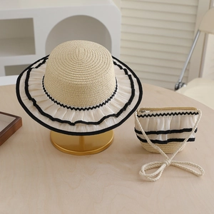 Detail of hand-woven straw hat and matching bag set with black lace trim and wave edges