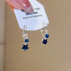 Macro detail of silver star drop earrings featuring deep blue zircon star pendants