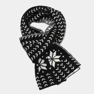 Detailed close-up of winter knitted scarf with black and white snowflake patterns