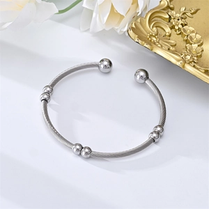 Close-up of a silver stainless steel cable wire cuff bracelet with polished round beads