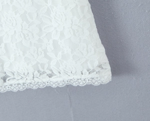 Gros plan détaillé de la dentelle florale blanche et de l'ourlet festonné de la robe