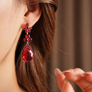 Macro view of vintage zircon flower and red teardrop pendant earring on model