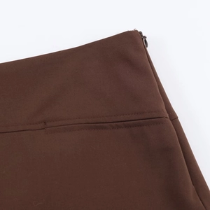 Detailansicht des verdeckten Reißverschlusses und der Twill-Struktur an der braunen Hose