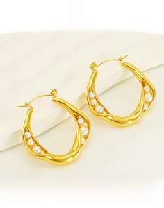 Close-up of irregular wave gold earrings with embedded white pearls in titanium steel
