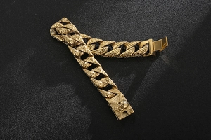Close-up of golden Cuban chain bracelet with snakeskin texture and skull clasp