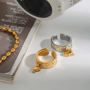 Close-up of gold heart rings and beaded bracelet on fashion magazine and white surface
