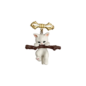 Cute white cat climbing a brown branch brooch with a golden bow on a white background
