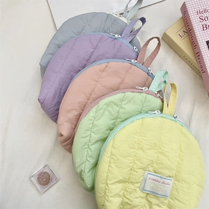 Detailed view of quilted shell-shaped cosmetic bags in five pastel colors with handles