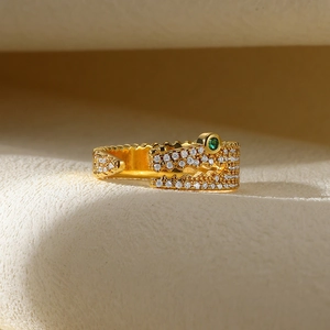 Detailed view of crocodile shaped gold ring with pavé diamonds and green gemstone eye