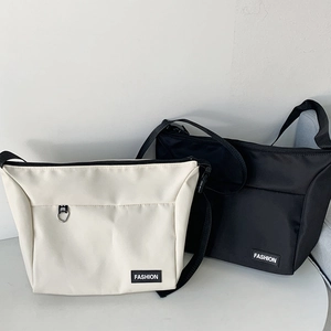 Detail view of cream and black canvas messenger bags with adjustable straps and fashion logo