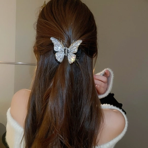 Detail of silver butterfly hair claw clip with zircons worn on a ponytail hairstyle