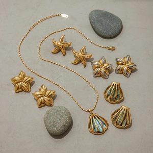 Detail of gold seashell and starfish jewelry set with abalone shell inlay on stone
