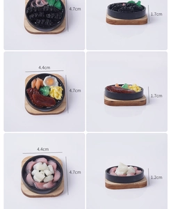 Macro view of miniature food keychains with steak and egg on wooden base details