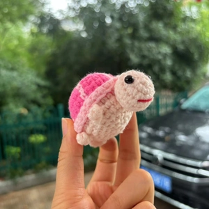 Handmade crochet positive turtle doll with pink shell in natural outdoor sunlight
