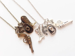 Detailed view of silver and bronze cowboy necklaces with pistol and horseshoe charms
