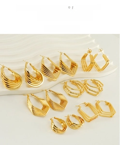 Detail of assorted geometric gold stainless steel earrings on a white textured stand
