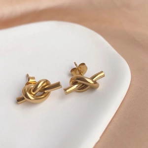 Minimalist golden knot earrings in a stylish ceramic tray with a modern design