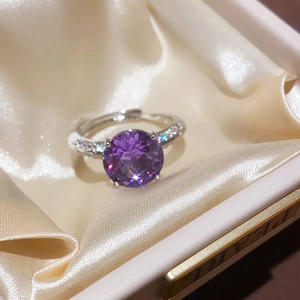 Detailed close-up of oval purple zircon ring with 4-claw setting on champagne satin