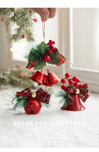 Christmas bell ornament with red metal finish, pine needles and buffalo plaid bow on snow