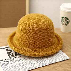 Detail of ginger yellow knitted dome bucket hat with honeycomb texture on wooden table