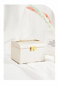 Detail of pearl white leather jewelry box featuring a golden lock and sturdy handle