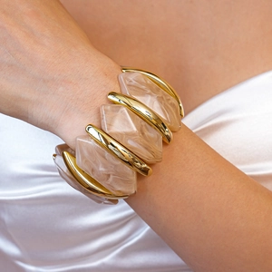 Détail du bracelet élastique en résine marbrée et alliage doré sur le poignet