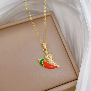Detailed close-up of a chili pendant necklace with red enamel and crystals on a leather box