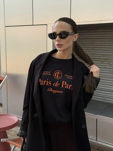 Λεπτομέρεια από μαύρο βαμβακερό T-shirt με πορτοκαλί λογότυπο Paris κάτω από μαύρο σακάκι