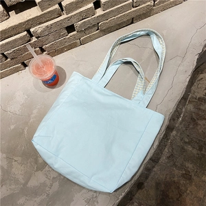 Detalle del bolso tote de lona azul claro con forro interior de cuadros amarillos y blancos