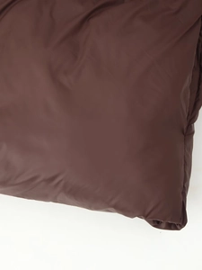 Gros plan du tissu de veste matelassée marron foncé montrant la texture lisse du nylon