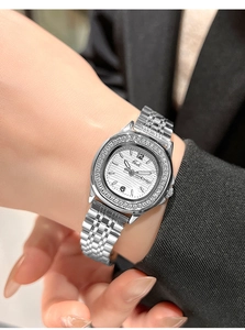 Detail of silver rhinestone watch with textured dial worn on wrist with black blazer