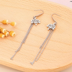Macro detail of silver tree of life earrings with cascading chain tassels on a wooden tray