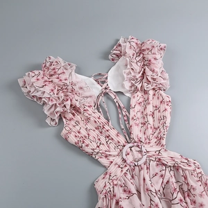 Détail d'une robe longue fleurie rose avec décolleté en V, manches volantées et boucle