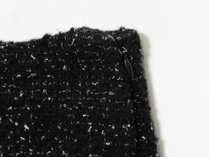 Détail de tissu en tweed noir aux fibres blanches avec une fermeture éclair en métal