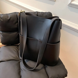 Nahaufnahme der schwarzen PU-Ledertasche mit breitem Gurt und goldenen Beschlägen