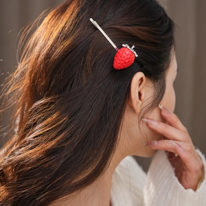 Vista dettagliata di un fermaglio per capelli a fragola rossa con strass indossato da modella
