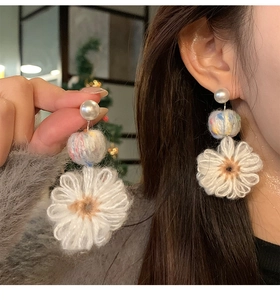 Detailed close-up showing yarn flower and pearl drop earrings texture and design