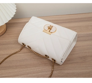 Detail of white V-quilted crossbody bag with gold chain strap and enamel turn-lock closure