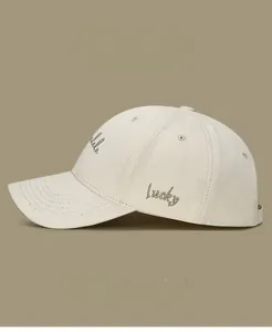 Close-up of Lucky embroidery on side of beige cotton twill baseball cap with fine texture