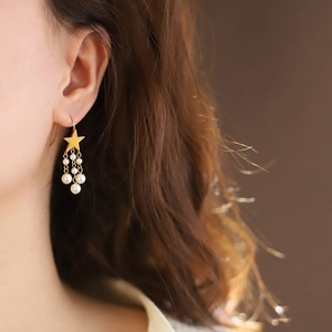 Gold star pearl tassel earrings worn by a model showcasing the elegant fringe design