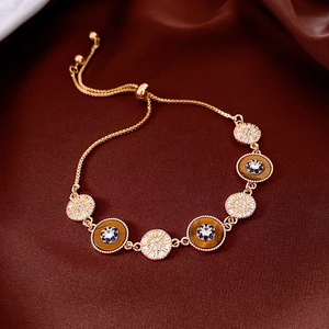 Gros plan du bracelet réglable plaqué or 18K avec oeil de tigre sur soie rouge