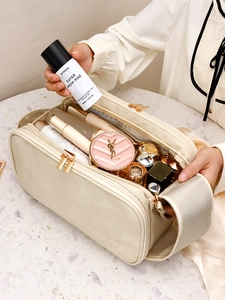 Large beige PU leather makeup bag with dual zippers and handle on marble background