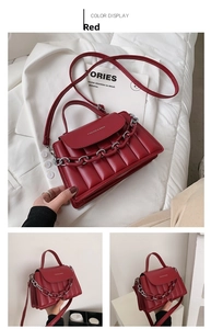 Detail of red quilted crossbody bag with silver chain strap and metal logo lettering