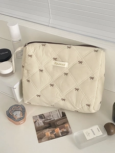 Borsa cosmetica trapuntata crema con ricamo a fiocco marrone e chiusura a cerniera